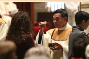 El P. Quy K. Pham da la comunión en la Misa de su ordenación. Foto: Sarah Webb / Catholic Philly.com